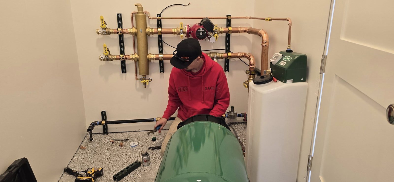The Other Buddy technician working on a hydronic distribution install with copper manifold, Grundfos circulator, dirt separator, and Webstone shutoff valves