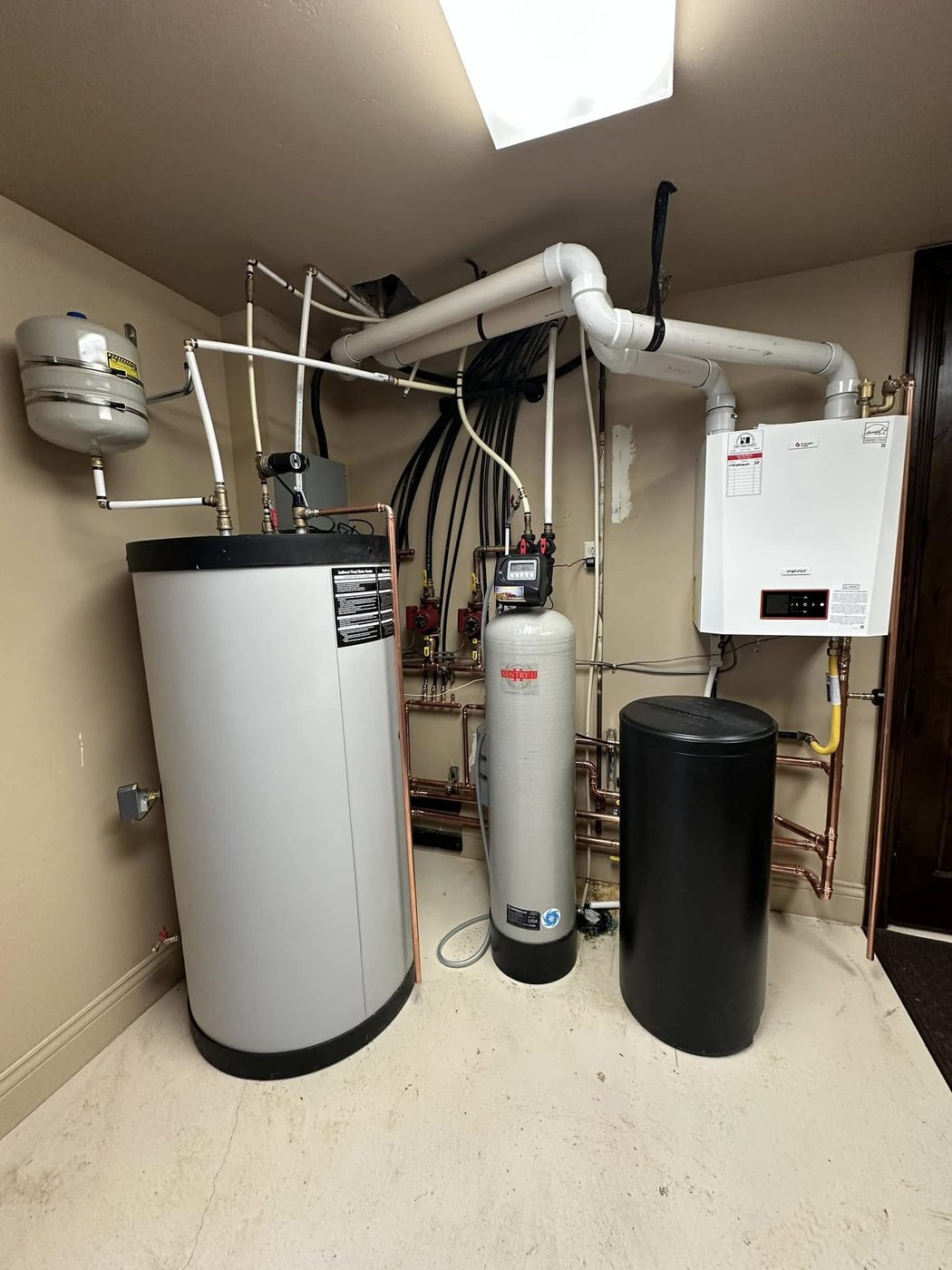Complete mechanical room install: wall-mount condensing boiler, indirect-fired water heater, water softener, brine tank, expansion tank, and full copper distribution