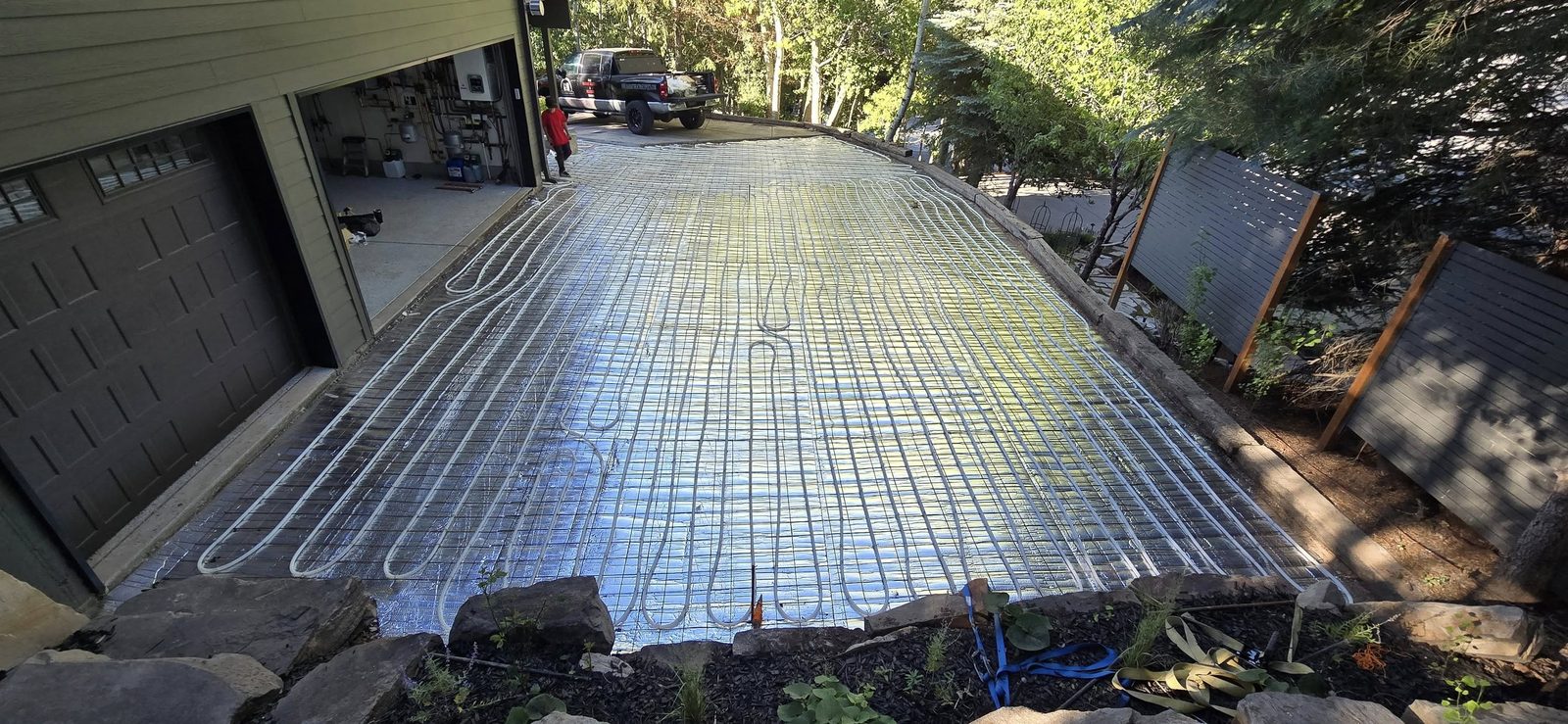 Snow-melt driveway installation showing PEX tubing loops laid over insulation before concrete pour
